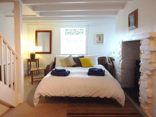 a bedroom with a bed with two blue towels on it at Little Barn Cottage in Portloe