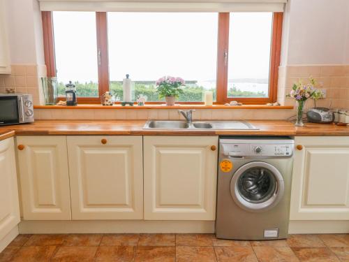 a kitchen with a sink and a washing machine at Mary Agnes Cottage in Eyeries