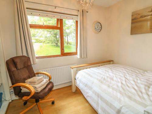 a bedroom with a bed and a chair and a window at 1 Ard Carraig in Portsalon