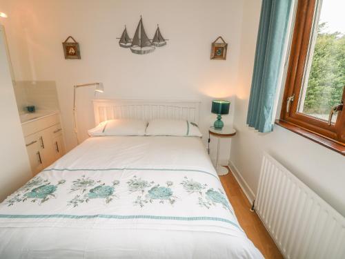 a white bed in a room with a window at 1 Ard Carraig in Portsalon