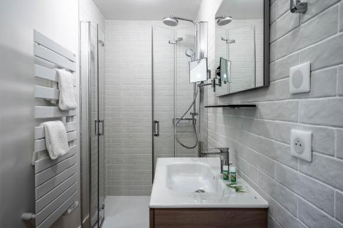 une salle de bain blanche avec un lavabo et une douche dans l'établissement La Grange des Pères, à Pringy
