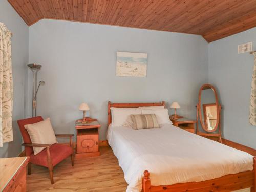 um quarto com uma cama, uma cadeira e um espelho em Rose Cottage em Ramsgrange