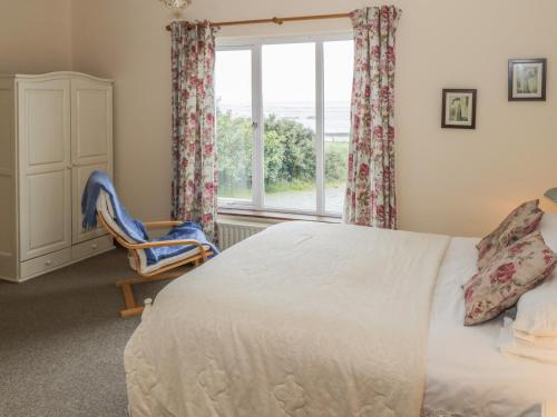 1 dormitorio con cama, ventana y silla en Seaspray, en Renvyle