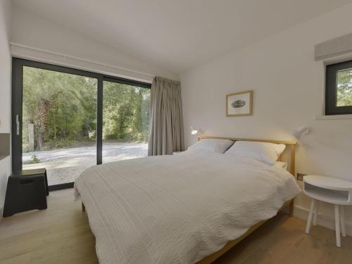 a bedroom with a bed and a large window at Grooms Cottage in Talaton