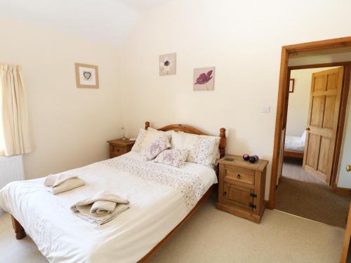 a bedroom with a bed with white sheets and a mirror at Marsh Cottage in Ashbourne