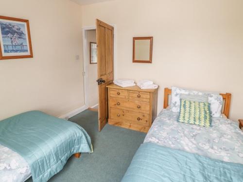 a bedroom with two beds and a wooden dresser at Pinecote in Stratford-upon-Avon