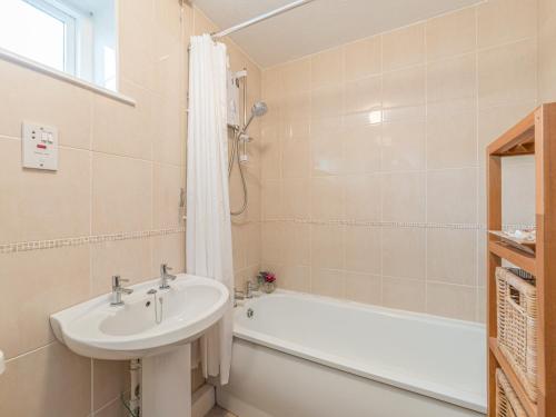 a white bathroom with a sink and a bath tub at Crumstone Corner in Seahouses