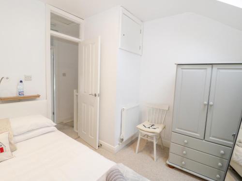 a white bedroom with a bed and a chair at Fishermans Cottage in Conwy