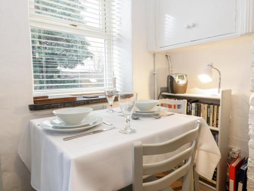 a table with a white table cloth and two glasses at Fishermans Cottage in Conwy