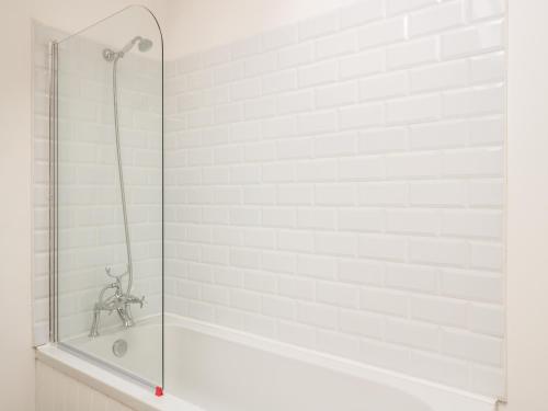 a bathtub with a glass shower door in a bathroom at Granary 2 in Hereford