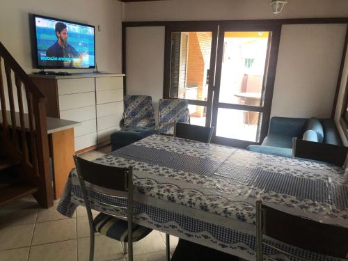 una sala da pranzo con tavolo, sedie e televisione di Linda casa com piscina em Bombinhas, espaço inteiro a Bombinhas