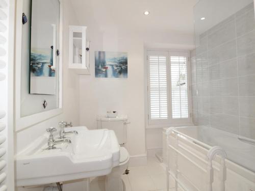 a white bathroom with a sink and a tub and a toilet at Dale Cottage in Crantock