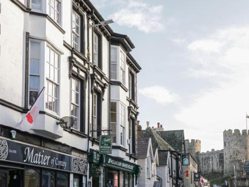 a street with buildings with a castle in the background at Castle Apartment in Conwy