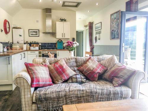 a living room with a couch and a kitchen at East Craigdhu Cow Byre in Beauly