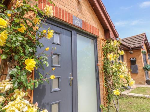 a blue door on a brick building with yellow flowers at Serendipity in Freshwater