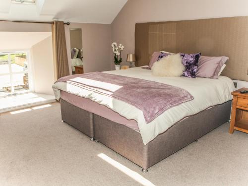 um quarto com uma cama grande e almofadas roxas em The Granary em Durham