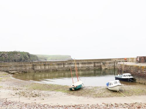 three boats sitting on the shore of a river at St Magnus Haven in Pennan