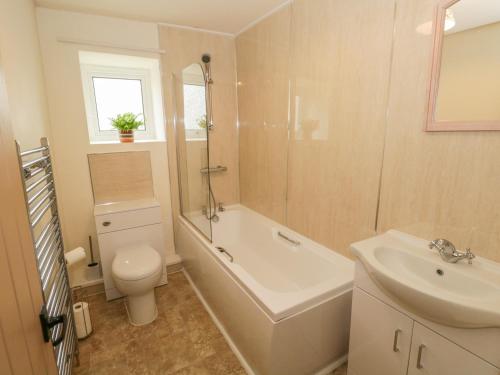 a bathroom with a toilet and a tub and a sink at Herdwick Cottage in Grange Over Sands