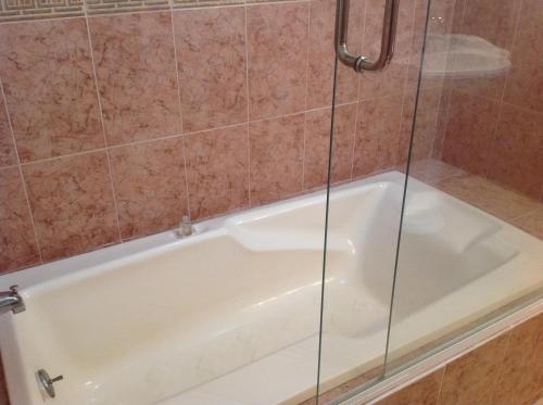 une baignoire blanche avec une porte de douche en verre dans l'établissement Hotel Providencia, à Talpa de Allende