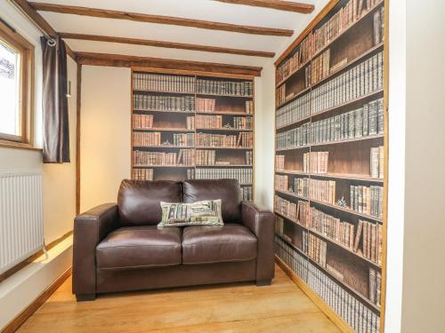 a leather chair in a library with bookshelves at Harbourne Oast in Tenterden