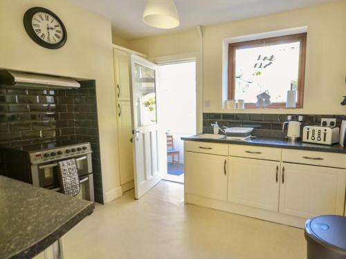 a kitchen with a sink and a clock on the wall at Ling Fell Cottage in Ulverston