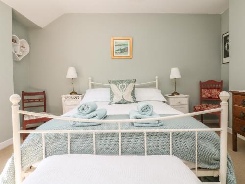 a bedroom with a white bed with towels on it at Primrose Cottage in Penryn