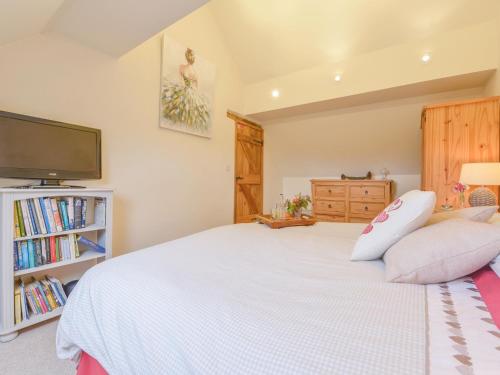 a bedroom with a large white bed and a tv at The Bolthole in Okehampton