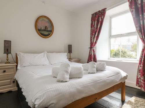 uma cama branca com toalhas num quarto em Mollys Cottage em St Just