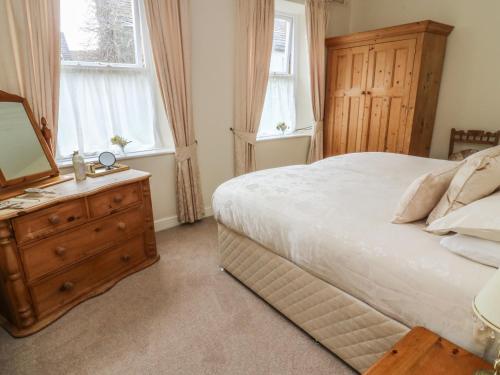 een slaapkamer met een bed en een dressoir met een spiegel bij Daisy's Holiday Cottage in Skipton