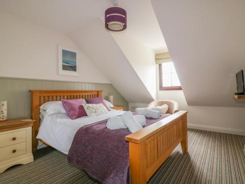 Schlafzimmer mit einem Bett mit weißer Bettwäsche und lila Kissen in der Unterkunft The Beach Hut in Crantock