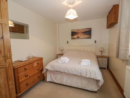 a bedroom with a bed and a dresser with towels on it at 1 Park Nook Close in Waberthwaite