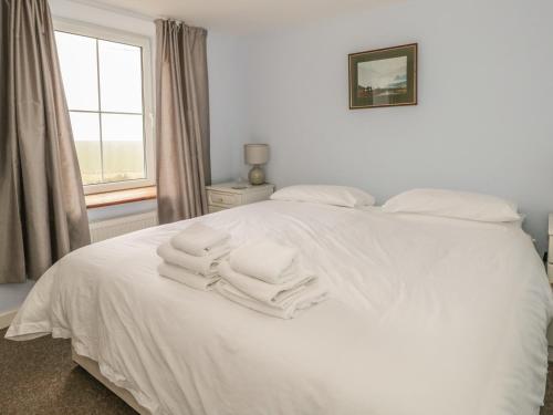 una camera da letto con un letto bianco e asciugamani di 2 Park Nook Close a Waberthwaite