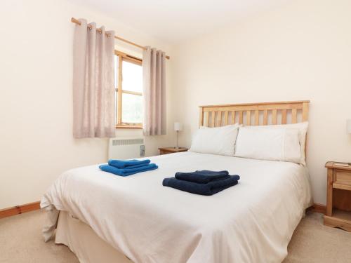 een slaapkamer met een wit bed en 2 blauwe handdoeken bij Cabin in Budock Water