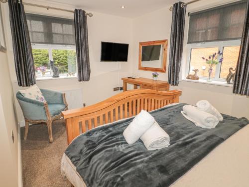 a bedroom with a bed and a chair and windows at River Cottage in Morpeth