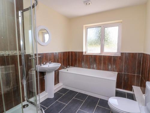 a bathroom with a tub and a sink and a toilet at Glanyrafon Bungalow in Rhayader