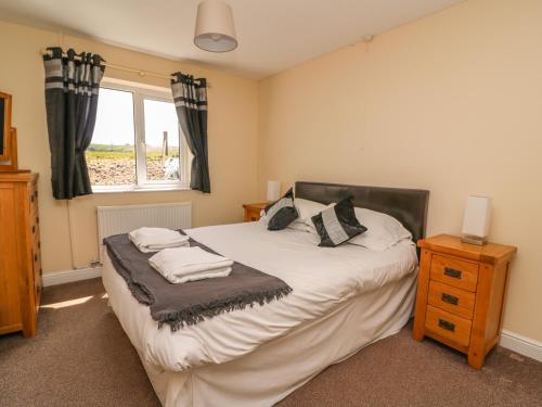 a bedroom with a bed with pillows and a window at Glanyrafon Bungalow in Rhayader