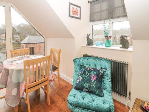 a dining room with a table and a chair with a pillow at River Cottage in Morpeth