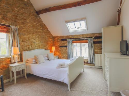 a bedroom with a bed and a tv in it at White Hart House in Burford