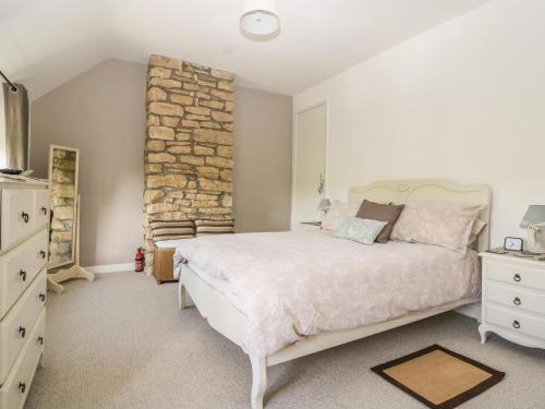 a bedroom with a large bed and a stone wall at Appin Cottage in Shipton under Wychwood