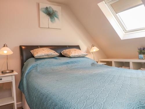 a bedroom with a blue bed with two pillows at Temple Mews in Stow on the Wold