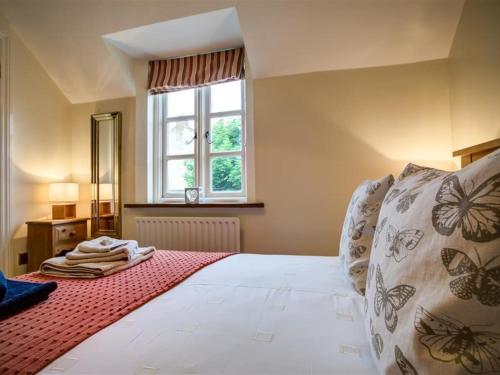 une chambre avec un grand lit blanc avec une fenêtre dans l'établissement Stow Cottage, à Stow-on-the-Wold