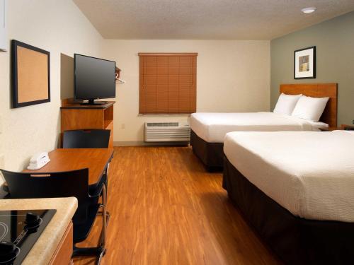 a hotel room with two beds and a flat screen tv at WoodSpring Suites Wilkes-Barre in Wilkes-Barre