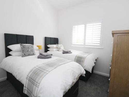 2 camas en una habitación con paredes blancas y ventana en Rowan Bank, Jacobs Wood en Keighley