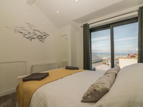 ein Schlafzimmer mit einem Bett und einem großen Fenster in der Unterkunft Harbour View Retreat in Brixham
