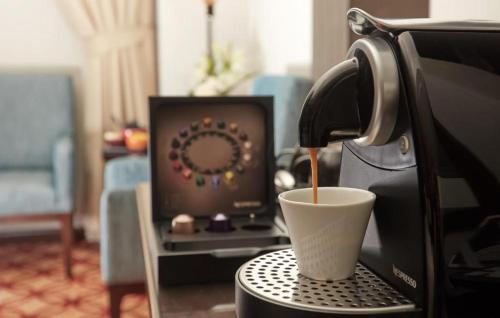 a cup of coffee sitting on top of a coffee machine at Dallah Taibah Hotel in Al Madinah