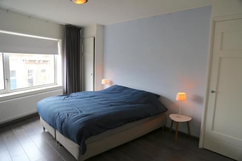 een slaapkamer met een blauw bed en een raam bij Beach Appartement in Vlissingen