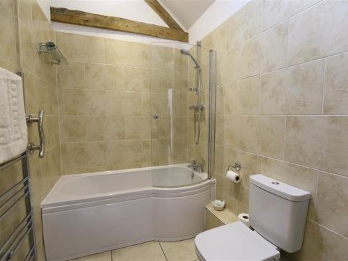 a bathroom with a tub and a toilet and a shower at The Old Dairy in Westbury on Severn