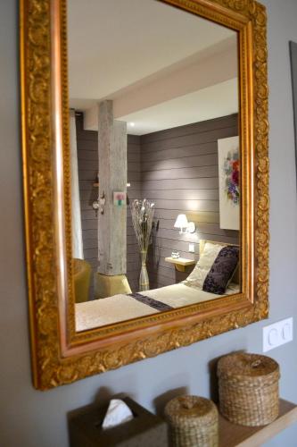 a mirror on a wall with a bed in a room at les tamaris in Castelnau-sur-Gupie