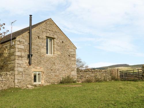 an old stone house in a field with a fence at Rushton Barn in Settle