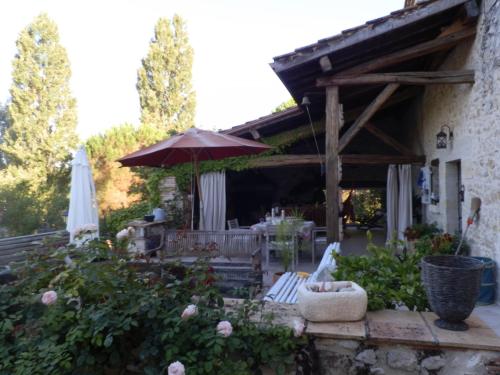 a patio with an umbrella and a table and chairs at les tamaris in Castelnau-sur-Gupie